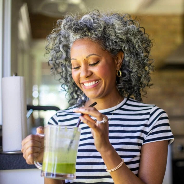 Eine glückliche Frau trinkt einen Smoothie