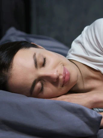 Eine Frau schläft in einer dunklen Bettwäsche