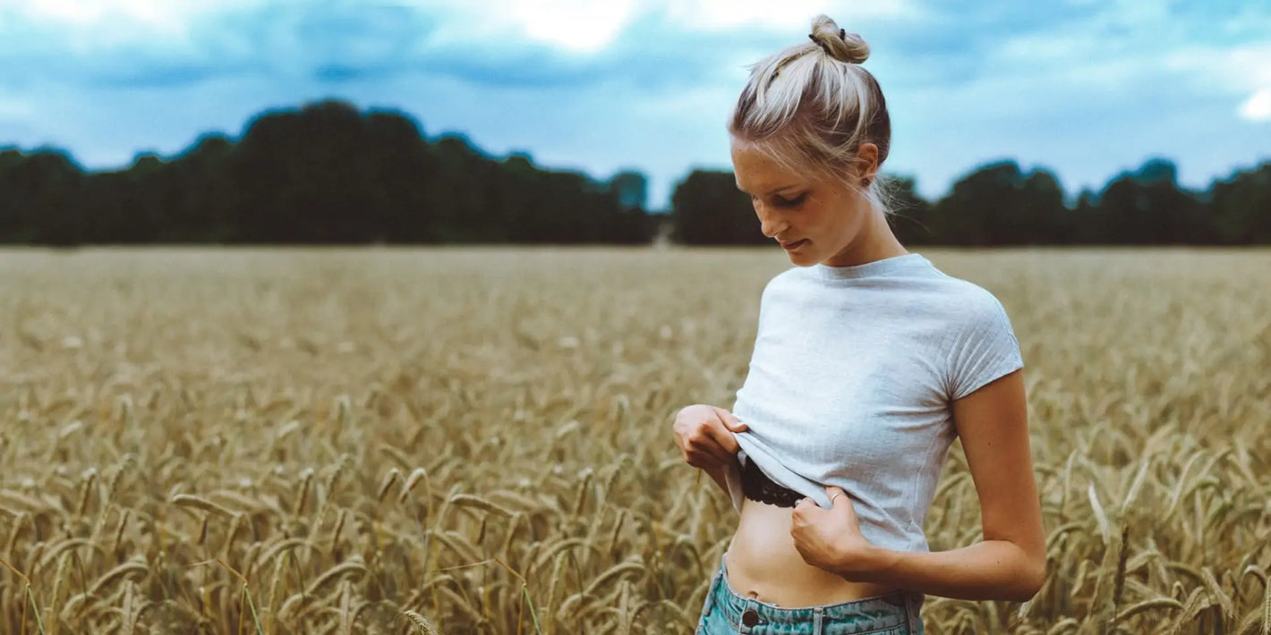 Junge Frau im Kornfeld die sich den Bauch hält