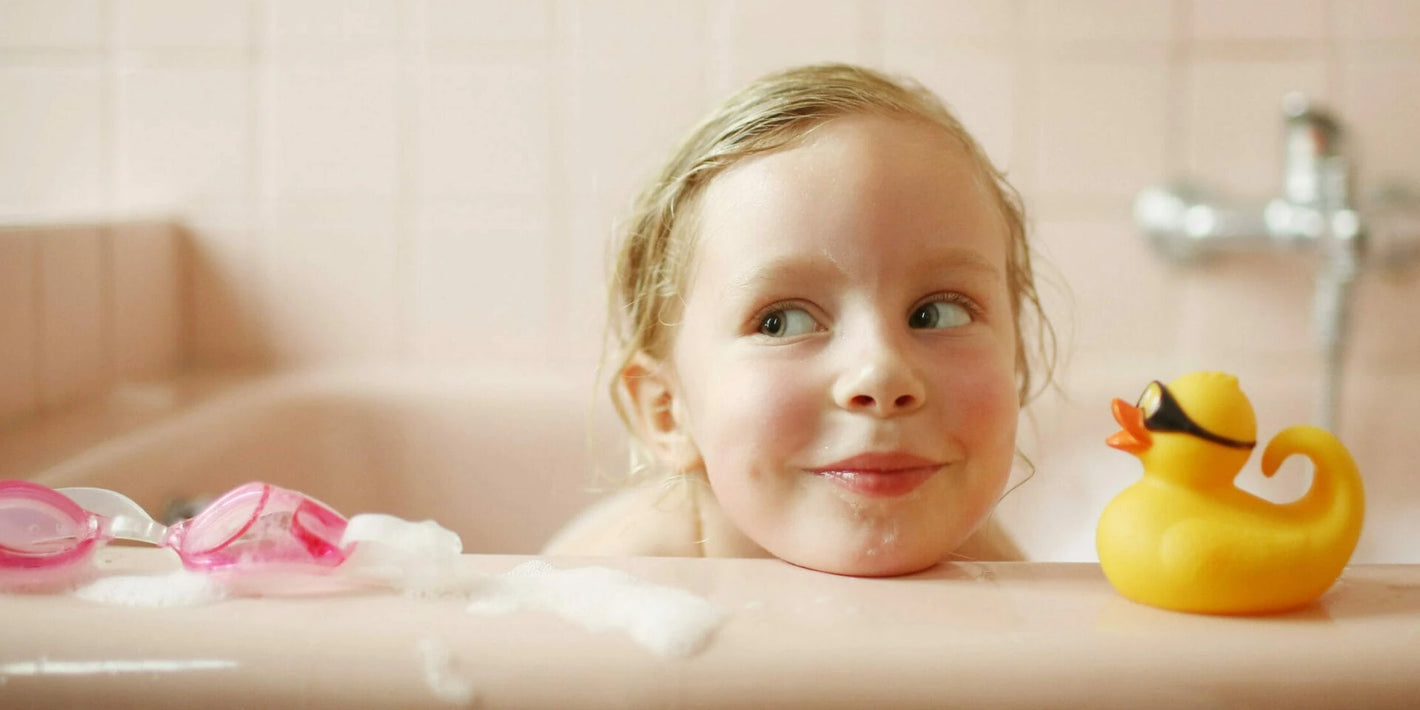 Junges Mädchen ist mit Badespielzeug in der Badewanne