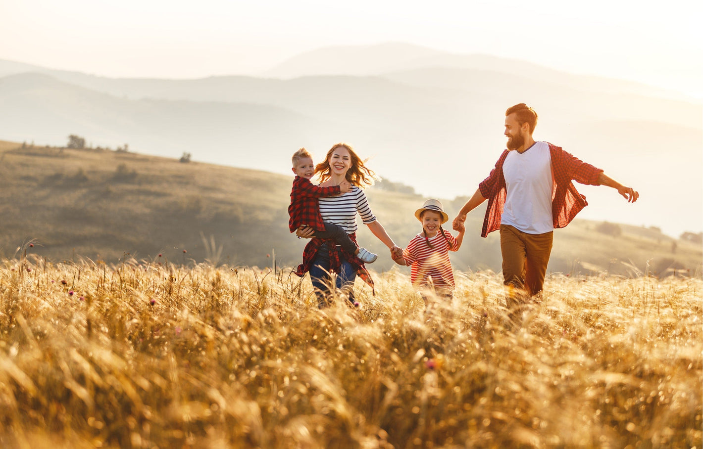 Familie mit zwei Kindern im Kornfeld bei Sonnenuntergang