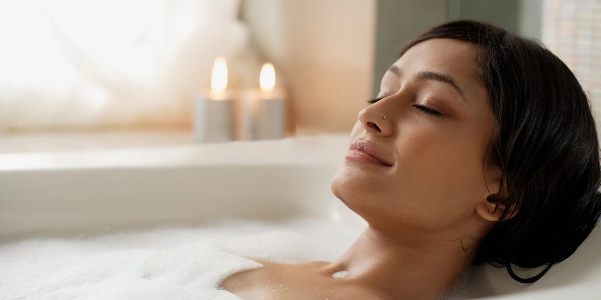 Eine Frau mit dunklen Haaren liegt entspannt in der Badewanne